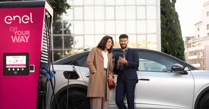 donna e uomo appoggiati alla macchina in ricarica