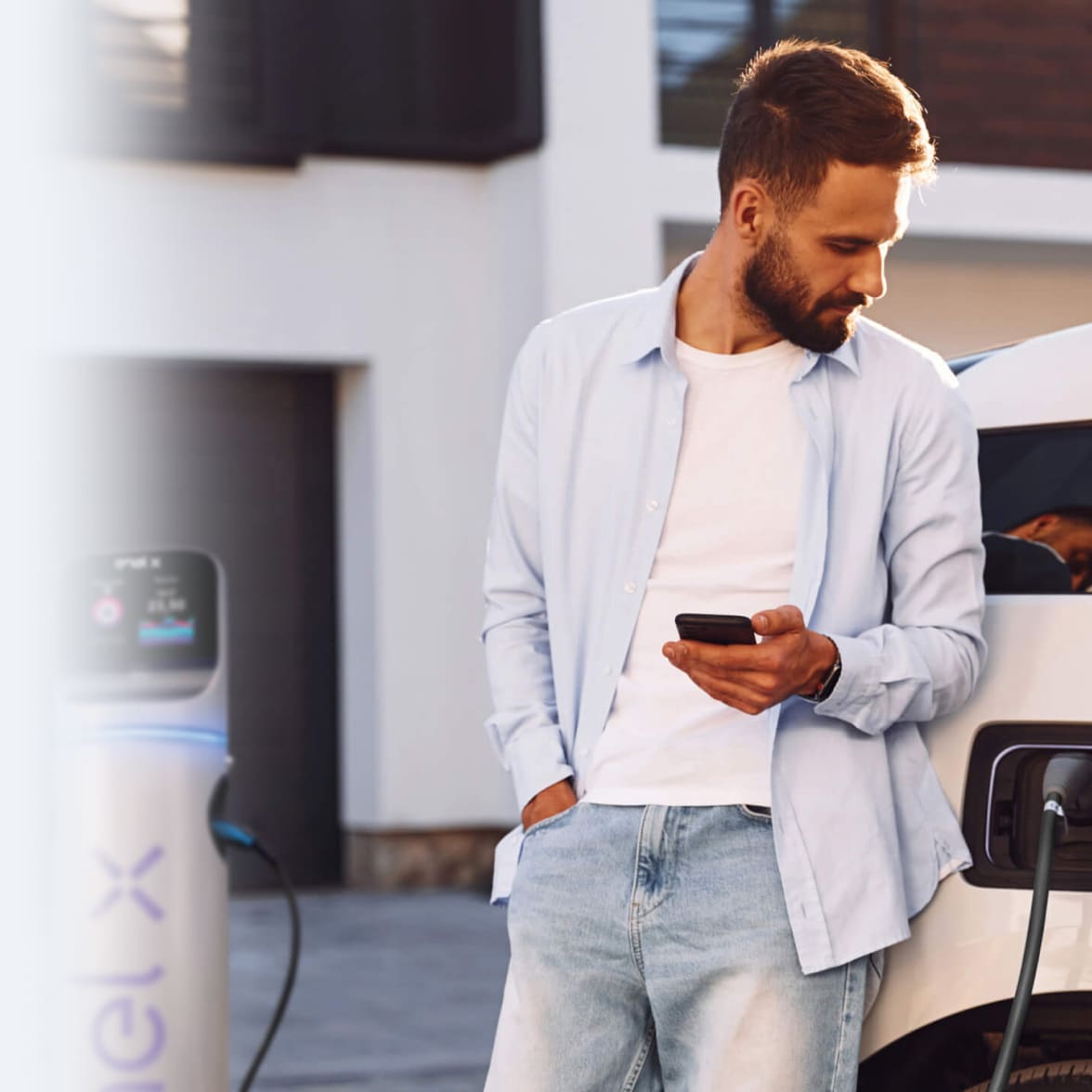 immagine ragazzo al cellulare appoggiato ad una macchina bianca