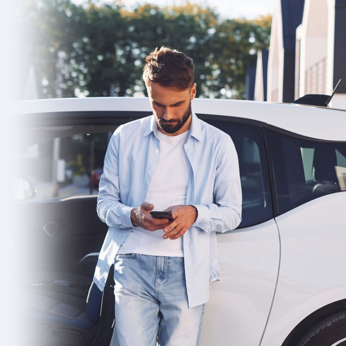 immagine ragazzo al cellulare appoggiato ad una macchina bianca