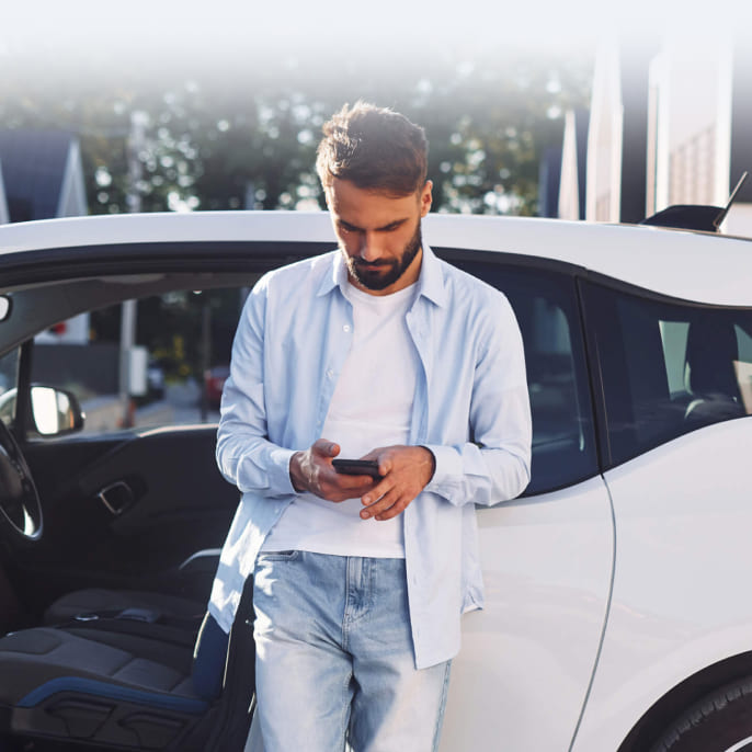 immagine ragazzo al cellulare appoggiato ad una macchina bianca