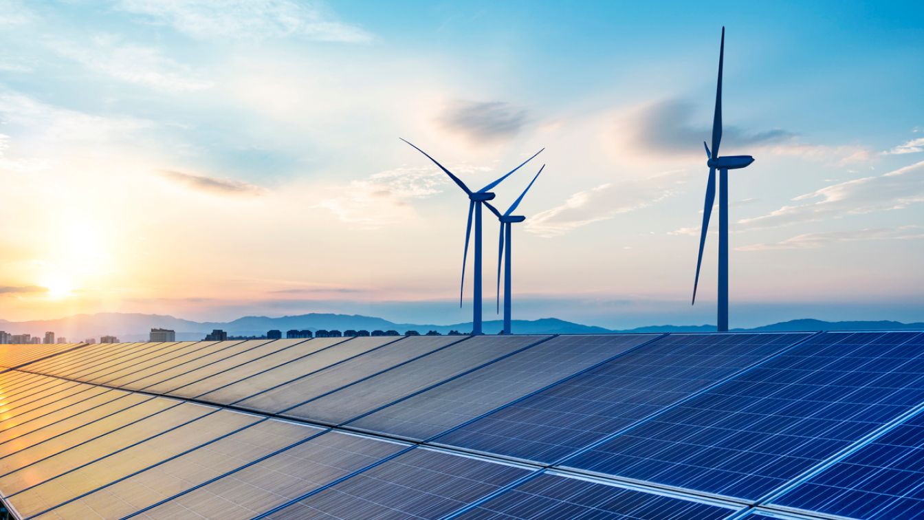 Pannelli solari e turbina eolica con tramonto sulla collina