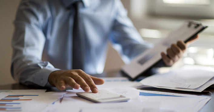 professionista che lavora a una scrivania con documenti finanziari e un calcolatore