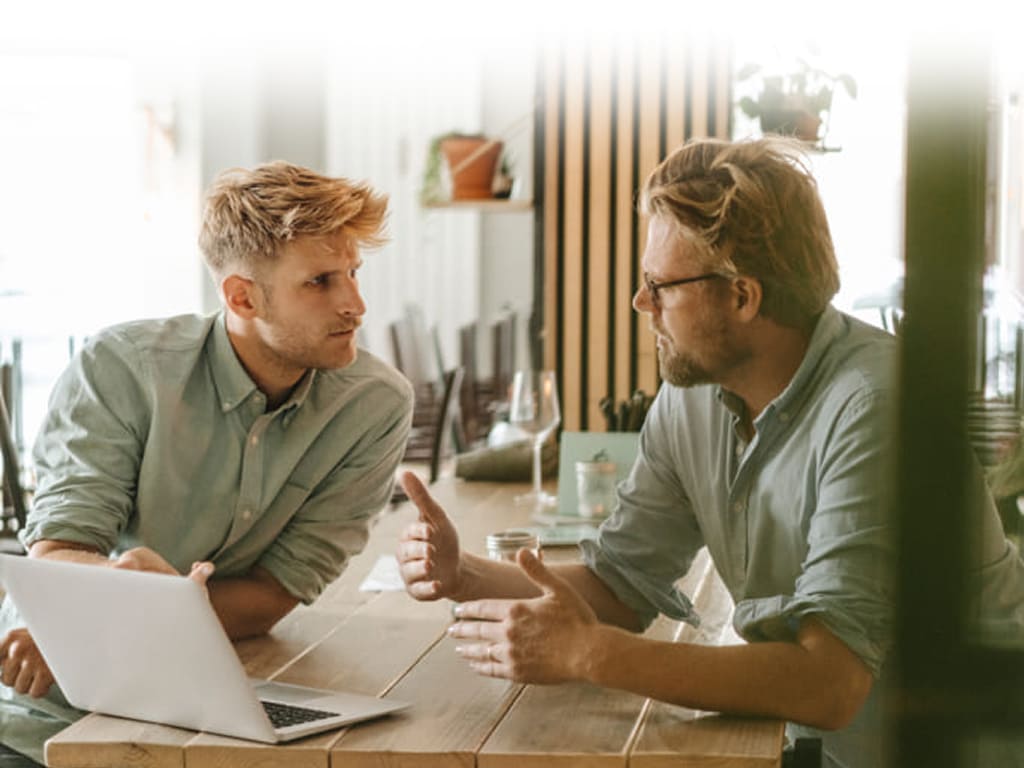 due uomini seduti al tavolo davanti ad un computer